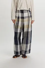 Pantalón Tokyo de lino con diseño a cuadros en tonos azul marino, beige y blanco. Presenta un corte amplio y relajado, cintura con cierre frontal de botón y tiras decorativas colgantes.