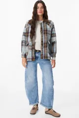 Chaqueta de corte holgado con estampado de cuadros en tonos beige, marrón y amarillo. Presenta cuello camisero en pana marrón, cierre frontal con botones y mangas largas con puños abotonados.