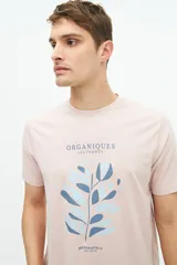 Remera de manga corta color rosado, con estampado frontal de hojas en tonos azules y texto "Organiquis Les Formes" y "Bisfield Est. 1971".