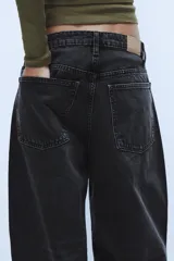 Jeans de tiro medio con diseño baggy barrel, confeccionados en denim color beige con efecto lavado. Presentan cinco bolsillos, costuras laterales torcidas y cierre frontal con cremallera y botón metálico.
