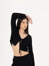 Cardigan de punto negro, de corte corto y diseño abierto con cierre de lazo frontal. Presenta mangas largas y una textura acanalada fina.
