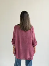 Sweater Ginebra de punto color magenta, con escote redondo, mangas largas con presilla y botón para ajustar, y diseño holgado con bajo asimétrico.