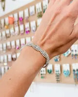 Pulsera de diseño trenzado compuesta por múltiples hileras de cristales brillantes engarzados en metal plateado.