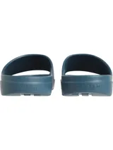 Ojotas tipo slide de color azul verdoso, con una banda ancha superior que presenta el logo 'CK' en relieve. La plantilla tiene textura acanalada para mayor agarre.