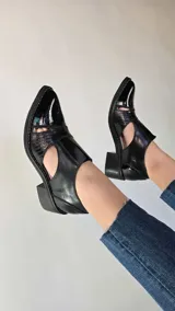 Zapatos de cuero negro con aberturas laterales, taco medio y detalles de textura en la puntera.