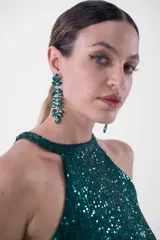 Vestido largo de fiesta con lentejuelas, compuesto por un top verde esmeralda con cuello halter y una falda negra ajustada con abertura lateral.