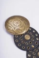 Cinturón de cuero con diseño de discos circulares superpuestos, adornados con tachas y hebillas redondas grabadas. Disponible en negro, marrón y con hebillas en tonos dorado y plateado.
