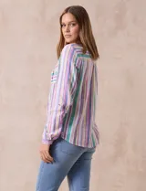 Blusa de lino estampada a rayas verticales en tonos blanco, verde, violeta, amarillo y rosa. Cuello a la base con escote en V y abertura central con botones. Delantera con bolsillos de parche. Mangas largas regulables con presilla y botón.