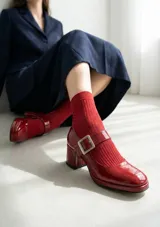 Zapato estilo Mary Jane de cuero vacuno con acabado charolado en color rojo. Presenta punta cuadrada, taco bloque de altura media y una tira con hebilla metálica sobre el empeine.