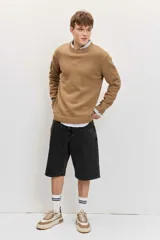 Sweater gris oscuro de punto con cuello redondo, manga larga y puños y dobladillo acanalados.