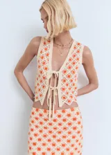 Minifalda de crochet color beige con estampado floral en tonos naranjas, corte recto y bajo festoneado.
