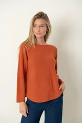 Sweater color naranja de tejido de punto suave, con cuello bote y mangas largas.