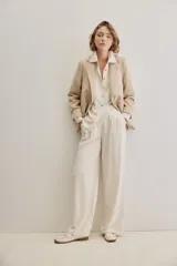 Pantalón negro de pierna ancha y calce fluido, con pinzas delanteras y bolsillos laterales.
