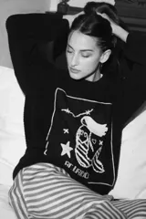 Sweater de punto oversize color crudo, con cuello redondo y diseño bordado a mano en el frente representando al signo Cáncer con un cangrejo, un corazón y una estrella.