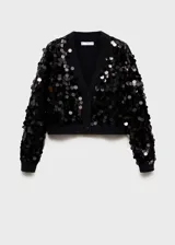 Cardigan negro de punto con cuello en pico y cierre frontal de botones. Presenta un diseño corto con mangas largas y puños elásticos, decorado íntegramente con lentejuelas circulares brillantes.