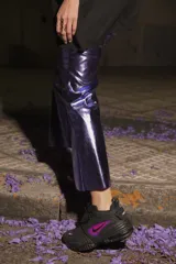 Pantalón de ecocuero color violeta metalizado, con corte capri semi oxford y tiro medio-alto. Presenta cierre frontal con botón metálico y bolsillos traseros.