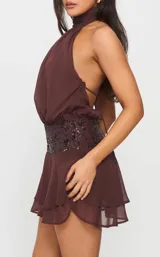 Vestido corto marrón con escote halter fruncido, cintura alta con aplique de lentejuelas y falda con volados en capas.