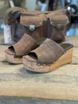 Zuecos con plataforma de madera y capellada marrón con textura croco y tachas doradas.