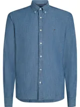 Camisa de chambray celeste de puro algodón, corte regular, con cuello abotonado, puños redondeados con dos botones y logo de Tommy Hilfiger bordado en el pecho.