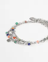 Set de tres pulseras plateadas con dijes de colores y dijes plateados.
