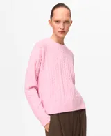 Jersey de punto trenzado color rosado, con cuello redondo y mangas largas de corte recto.
