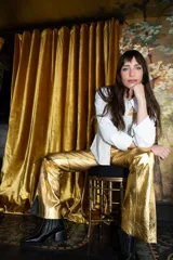 Pantalón dorado de corte acampanado con aberturas laterales en el ruedo.