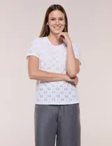 Remera blanca de calce recto con diseño de bordado calado estilo broderie, cuello redondo clásico y mangas cortas.