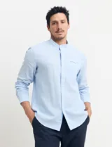 Camisa de cuello mao y manga larga, confeccionada en una mezcla de lino y algodón. Presenta un diseño de corte recto con botones en tono natural y un bolsillo pequeño en el pecho.