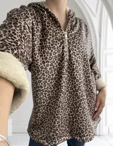 Buzo con capucha color marrón con estampado animal print de leopardo y cierre frontal con cremallera. Interior y puños de piel sintética color crema.