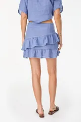 Minifalda amarilla confeccionada en lino italiano, de corte en A, con diseño de doble volado escalonado y detalles de terminación con bordado calado.