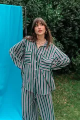 Conjunto de camisa y pantalón de fibrana con diseño a rayas verticales en tonos verde, blanco, violeta y negro. La camisa es de corte amplio con bolsillos frontales en el pecho, y el pantalón es de corte recto y holgado.