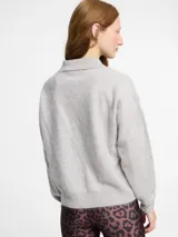 Sweater de punto de cachemira color turquesa con cuello polo y cierre frontal de tres botones. Presenta una textura suave tipo pelo, manga larga y terminaciones acanaladas en puños y ruedo.