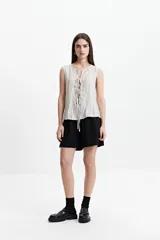 Blusa sin mangas color gris claro con textura rayada vertical y lazo ajustable en el escote.