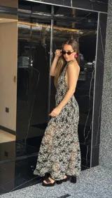 Vestido midi de encaje floral color beige sobre base negra, con cuello halter y falda con vuelo.