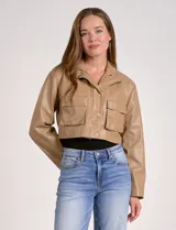 Chaqueta corta de eco cuero color tostado, con cuello alto, cierre frontal con botones a presión y bolsillos de solapa en el pecho. Tiene forro interno a tono.