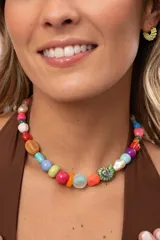 Gargantilla corta multicolor elaborada con una mezcla de cuentas de cerámica, acrílico, cristales y piedras naturales, que incluye un dije en forma de caracol verde.