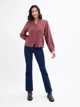 Blusa de algodón color bordó con estampado de lunares claros, cuello mao, cierre frontal con botones y mangas largas.