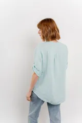 Camisa color topo confeccionada en lino, de corte holgado, con escote en V abotonado, bolsillo frontal y mangas 3/4 arremangables.