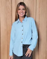 Camisa de corte clásico en denim color celeste claro, con cuello camisero, cierre frontal de botones y mangas largas con puños abotonados.