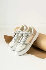Championes urbanos de diseño combinado en tonos plateado, beige y tostado. Presentan cordones al tono, suela de goma blanca y paneles laterales con textura diferenciada.
