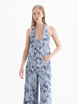 Chaleco de denim de algodón con diseño estampado de efecto desgastado, escote en V pronunciado, cierre frontal con botones y bolsillos frontales.