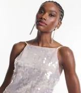 Vestido corto con escote cuadrado y breteles finos ajustables, confeccionado en tejido de lentejuelas metalizadas con forro.