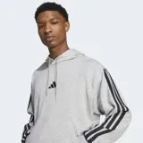 Canguro Adidas gris con capucha, cordón ajustable, bolsillo tipo canguro, hombros caídos, puños y dobladillo acanalados, dobladillo trasero ligeramente más corto y las icónicas tres rayas negras en las mangas.