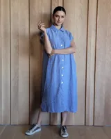 Túnica midi de corte holgado, color azul, con cuello camisero, cierre frontal de botones y mangas cortas. Presenta tajos laterales en el ruedo.