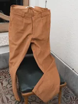 Pantalón de pana color marrón claro, de corte ancho y tiro alto, con bolsillos laterales y traseros.