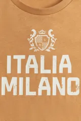 Remera de algodón color mostaza con cuello redondo y manga corta. Estampado frontal en blanco con el texto "ITALIA MILANO" y un escudo heráldico.