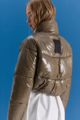Campera puffer corta a la cintura, color verde militar con acabado brillante. Presenta cuello alto, cierre frontal completo y bolsillos laterales con cierre invisible.
