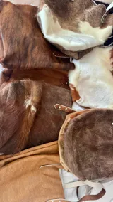 Bolso tipo tote de cuero con pelo color marrón y blanco, con manijas de cuero crudo.