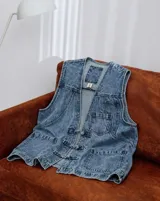 Chaleco de denim con efecto lavado, cierre frontal con nudos decorativos, bolsillos frontales y diseño sin mangas.