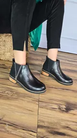 Botinetas de cuero napa color tostado, con taco bajo de madera de 3 cm, elástico lateral y panel trasero con textura de símil piel de serpiente. Cuentan con un cierre lateral decorativo y funcional.